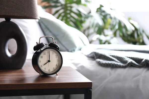 Alarm clock on table in bedroom — Stock Photo, Image