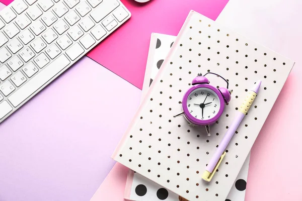 Computer keyboard, notebooks and alarm clock on color background — Stock Photo, Image