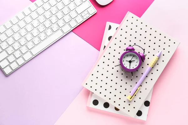 Computer keyboard, notebooks and alarm clock on color background — Stock Photo, Image