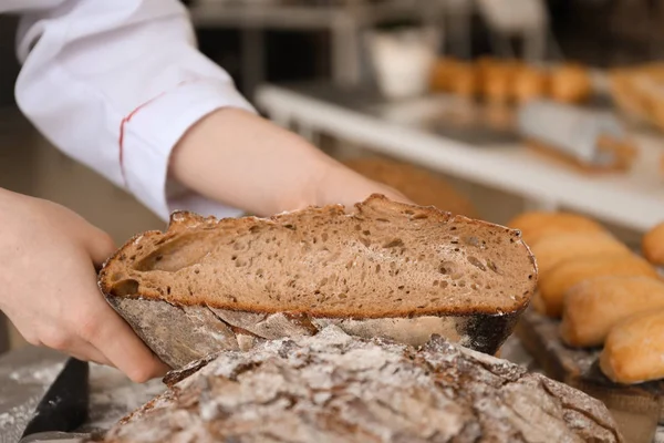 Female baker with tasty fresh bread, closeup