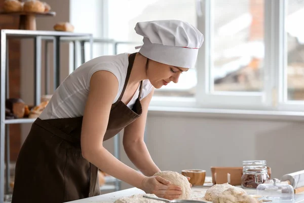 Female baker making dough in kitchen