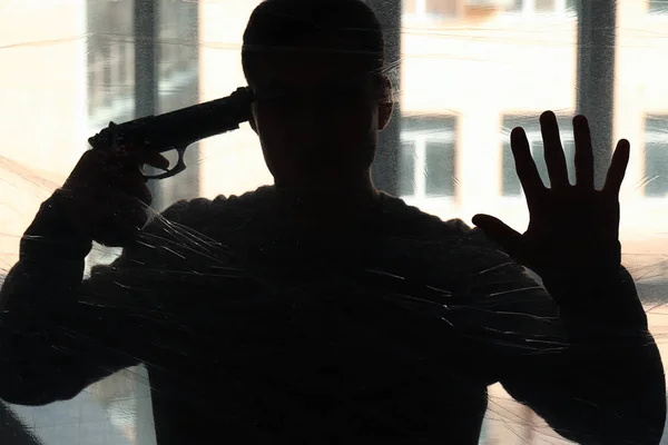 Σιλουέτα του νεαρός άνδρας με όπλο πρόκειται να διαπράξουν αυτοκτονία κοντά στο παράθυρο — Φωτογραφία Αρχείου