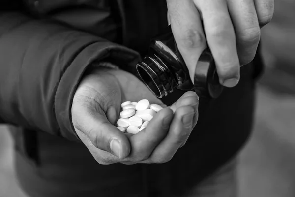 Foto en blanco y negro del suicida masculino tomando píldoras al aire libre, primer plano —  Fotos de Stock