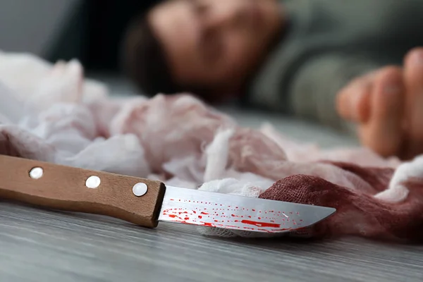 Bloodstained knife and dead man on floor. Suicide awareness concept — Stock Photo, Image