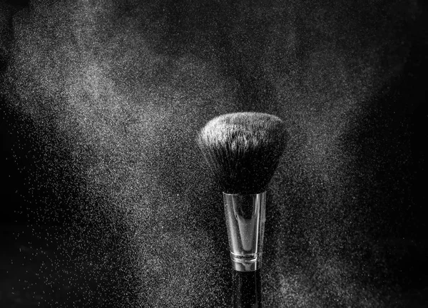 Make-up borstel en uitbarsting van poeder op donkere achtergrond — Stockfoto