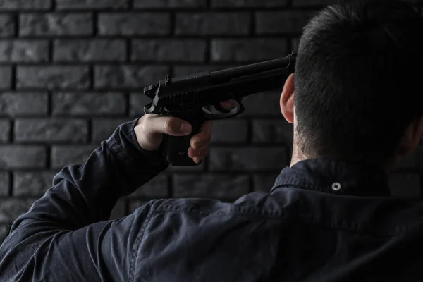 暗い背景に自殺する銃に行くと若い男 — ストック写真
