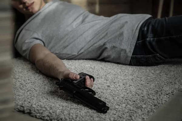 Body of man with gun after committing suicide lying on floor