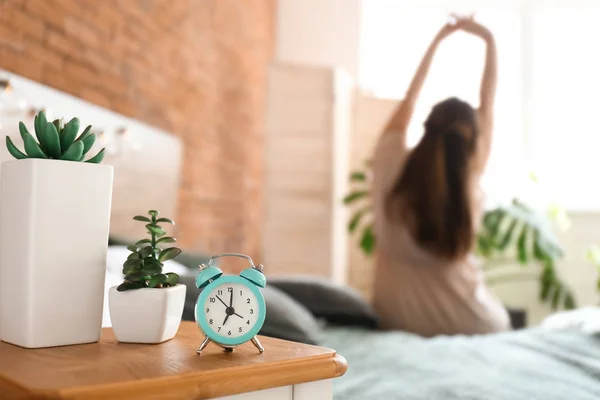 Alarm clock on table in bedroom of young woman — Stock Photo, Image