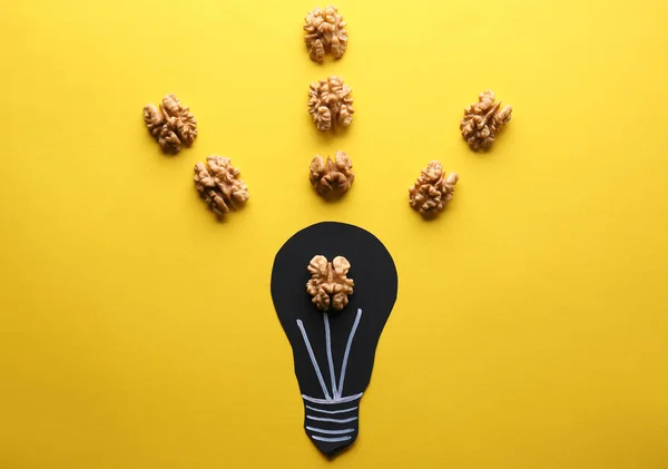 Light bulb with tasty shelled walnut on color background — Stock Photo, Image