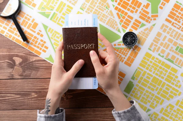 Female hands with passport and map on wooden table — Stock Photo, Image