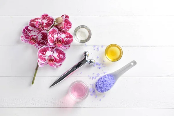 Facial massage tool with cosmetic products on white wooden background — Stock Photo, Image