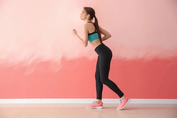 Deportiva joven corriendo contra la pared de color — Foto de Stock