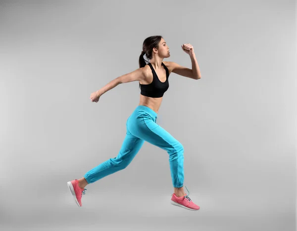 Спортивная молодая женщина бежит на легком фоне — стоковое фото