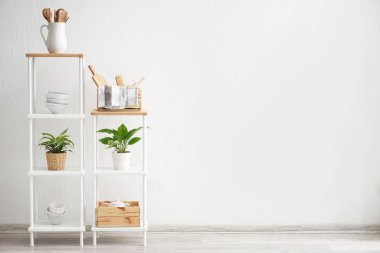 Raflar mutfak eşyaları yakınındaki beyaz duvar ile