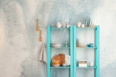 Temiz yemekler ile mutfak eşyaları hafif duvarının yakınında raflarda ayarla