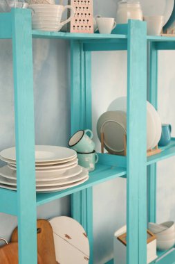 Temiz yemekler ile mutfak eşyaları hafif duvarının yakınında raflarda ayarla