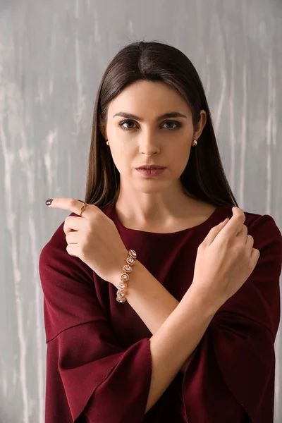 Young woman with beautiful jewelry on grunge background — Stock Photo, Image