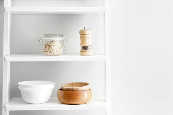 Shelves with kitchenware near white wall — Stock Photo, Image