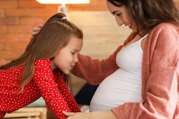 Madre embarazada con hija pequeña en casa — Foto de Stock