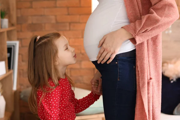 Meisje met zwangere moeder thuis — Stockfoto