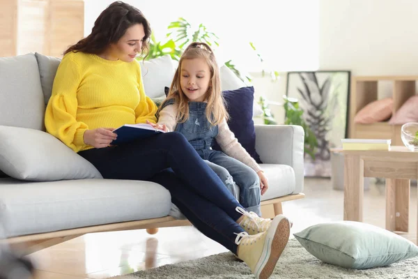 Zwangere moeder met dochter lezing boekje thuis — Stockfoto