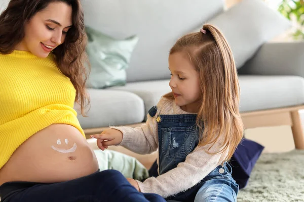 Little daughter drawing on belly of mother at home — Stock Photo, Image