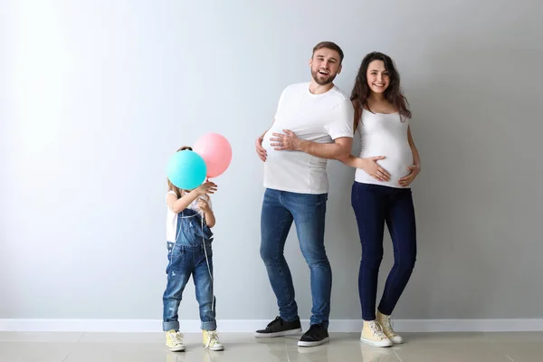 Gelukkige familie verwachten baby in de buurt van lichte muur — Stockfoto