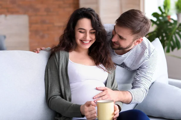 Lyckliga gravida par vilar hemma — Stockfoto