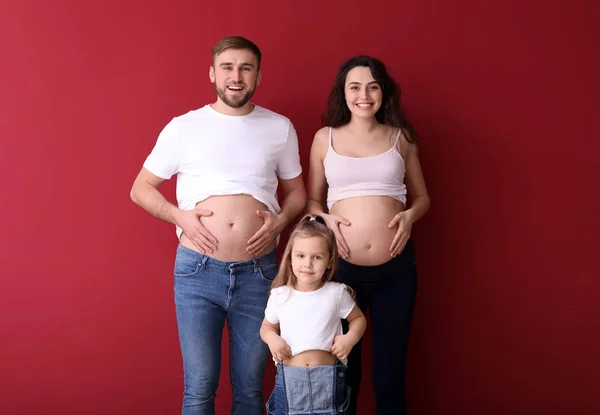 Happy family expecting baby on color background