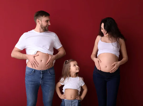 Gelukkige familie verwachten baby op kleur achtergrond — Stockfoto