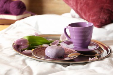 Tepsi ile fincan kahve, kek ve çiçek yatakta