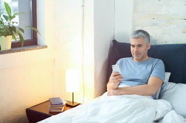 İle hareket eden telefon yatakta olgun adam