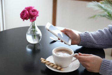 Cep telefonu masada kahve içme olan kadın