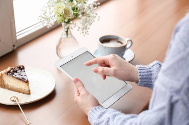 Genç kadın ile tablet Pc pencere yakınındaki masada oturan