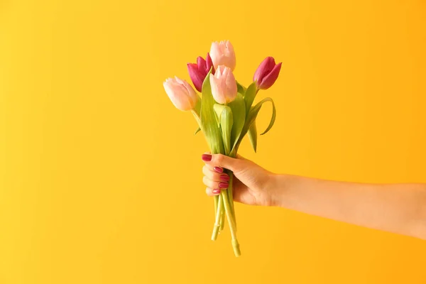 Mano femenina con ramo de tulipanes sobre fondo de color — Foto de Stock