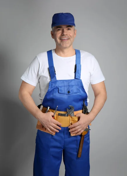 Volwassen werknemer in uniform op grijze achtergrond — Stockfoto