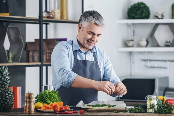 Mature man cooking tasty pizza at home — Stock Photo, Image