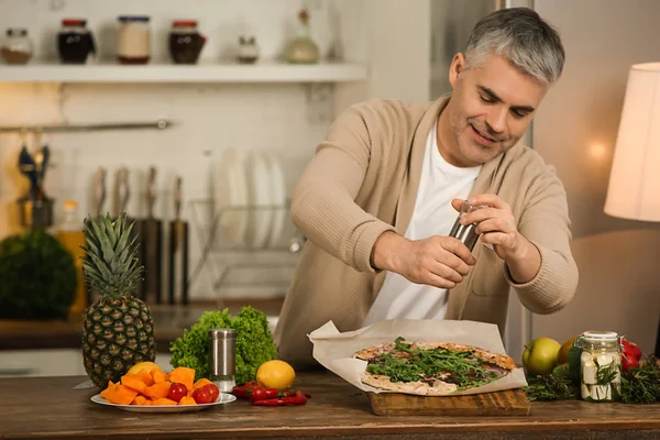 Mature man cooking tasty pizza at home — Stock Photo, Image