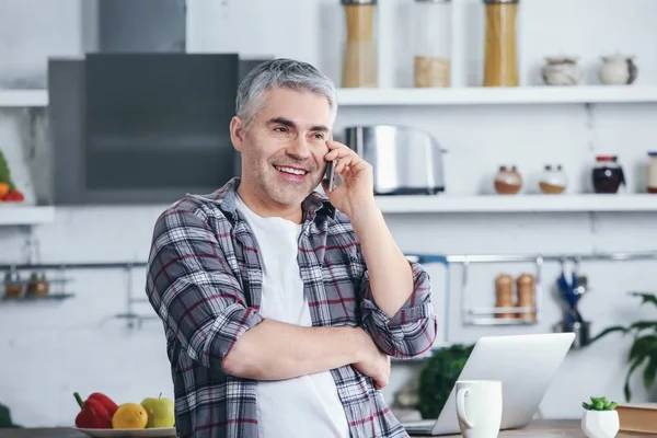 Mature man talking by phone in kitchen — Stock Photo, Image