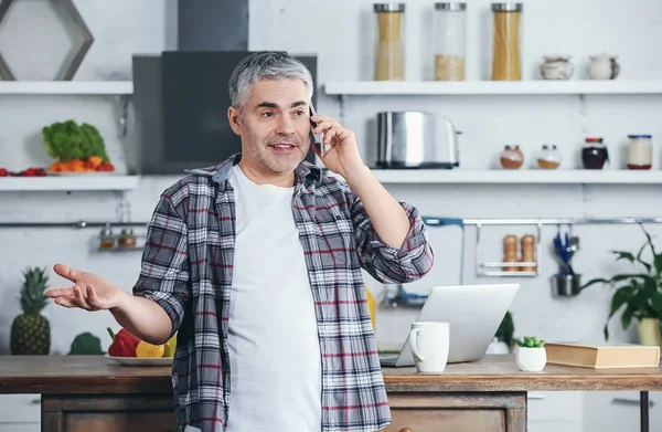 Uomo maturo che parla per telefono in cucina — Foto Stock