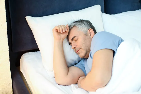 Зрелый мужчина спит в постели дома — стоковое фото