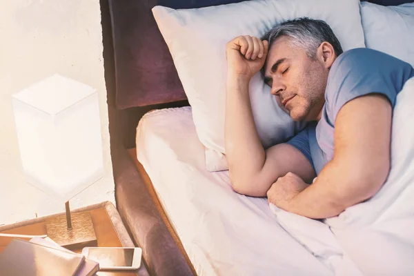 Зрелый мужчина спит в постели дома — стоковое фото