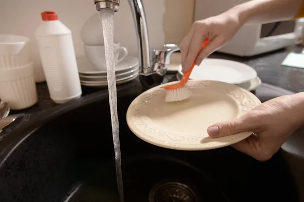 Woman washing dish in sink