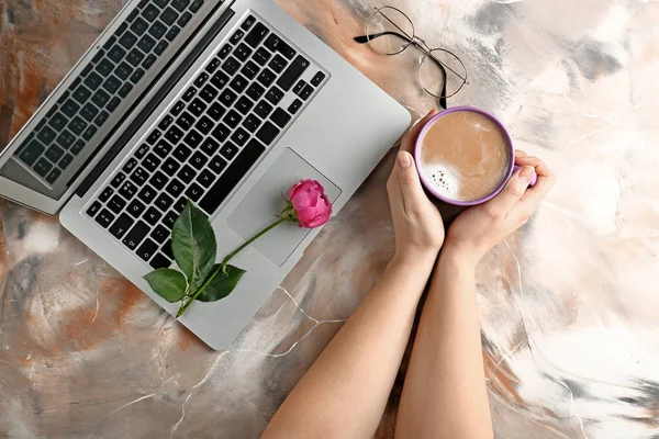 Manos femeninas con taza de café y portátil sobre fondo de color —  Fotos de Stock