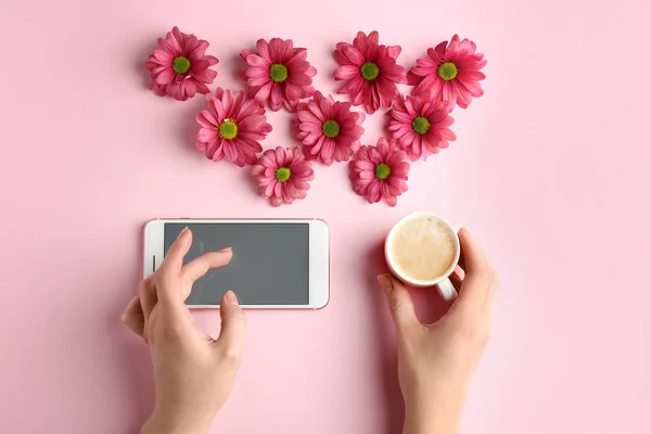 Weibliche Hände mit Handy und Tasse Kaffee auf farbigem Hintergrund — Stockfoto