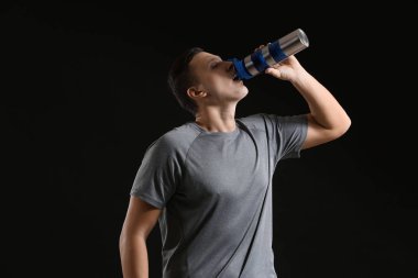 Şişe su koyu arka plan ile sportif genç adam