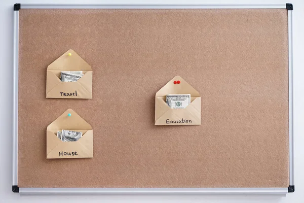 Envelopes with money for different needs on board. Concept of savings