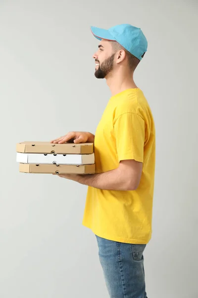 Mensajero joven con cajas de pizza sobre fondo claro — Foto de Stock