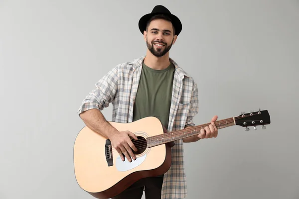 Handsome musician with guitar on light background — Stock Photo, Image