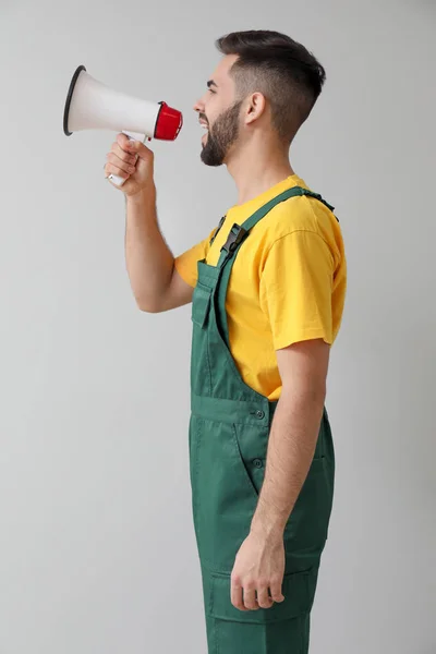 Handsome worker with megaphone on light background — Stock Photo, Image